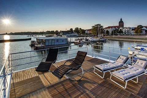 Urlop na łodzi w pierwszym rzędzie: nowoczesny pływający dom jest mocno położony w małym porcie miejskim Ribnitz-Damgarten. Rano wychodzisz z sypialni i cieszysz się pięknym widokiem na nadmorskie środowisko, a wieczorem świętujesz zachód słońca z za...